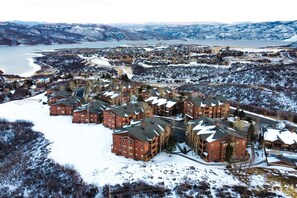 Un resort cubierto de nieve con varios edificios rojos, un lago al fondo y un paisaje montañoso.