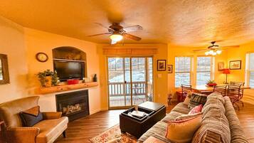A cozy living room with a fireplace, a television, and a large sofa.