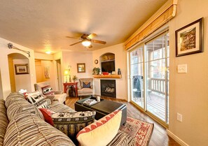 A living room with a sofa, armchairs, a fireplace, and a large window.