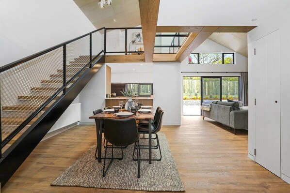 A modern interior with a dining area, staircase, and a view of the outdoors.