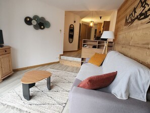 Uma sala de estar moderna com um sofá cinza, uma mesa de centro de madeira e um tapete estampado.