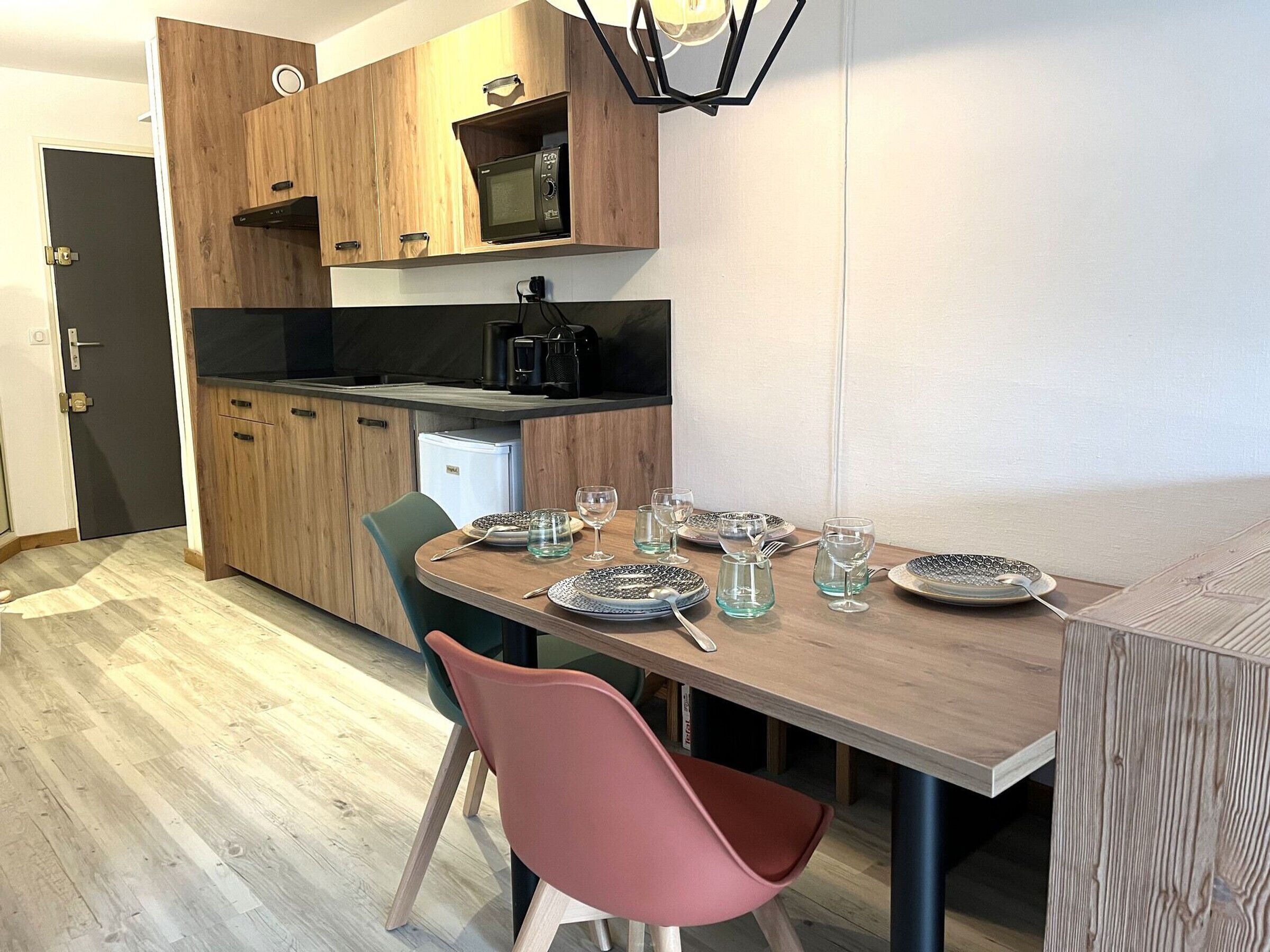 A compact kitchen with wooden cabinets, a microwave, and a coffee maker.