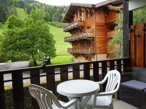 A wooden chalet with a balcony, white plastic chairs, and a round table. - Studio near center and slopes for 4 pers. in Morzine (Morzine)