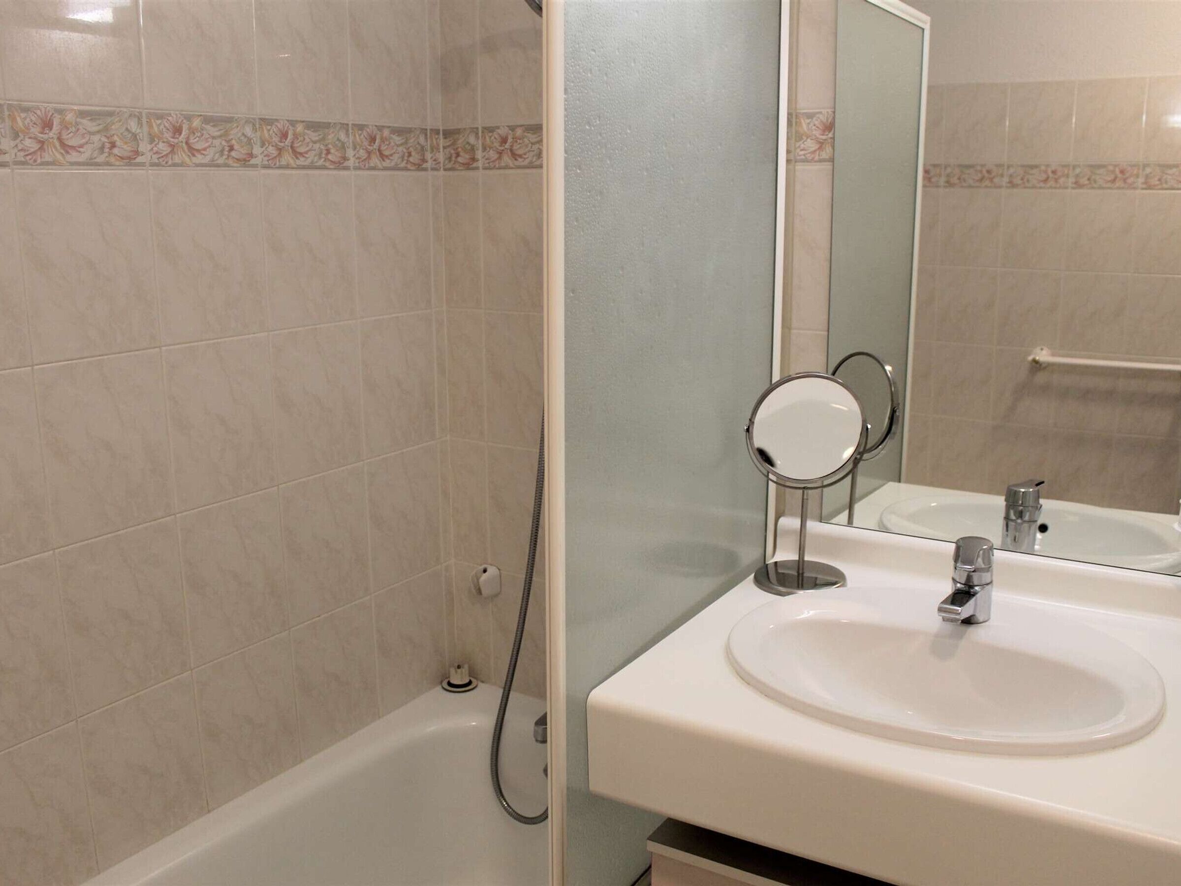 A bathroom with a bathtub, a sink with a mirror, and a towel rack.