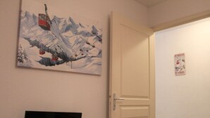 Una stanza con TV a muro, una porta e un quadro.