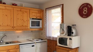 Una cucina compatta con mobili in legno, un forno a microonde, una macchina da caffè e un frigorifero.