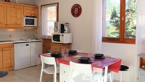 Una cucina con mobili in legno, un forno a microonde, una macchina da caffè e un tavolo da pranzo con sedie.