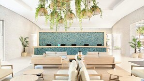 A modern lounge area with a seating arrangement, a decorative wall, and hanging plants. - FERGUS Club Mallorca Waterpark (Calvia)