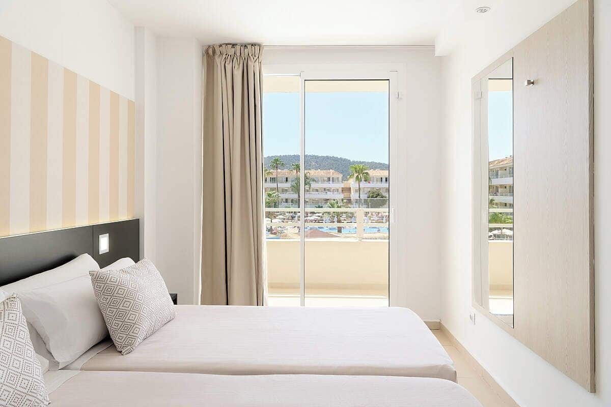 A hotel room with a bed, a view of the beach, and a balcony.
