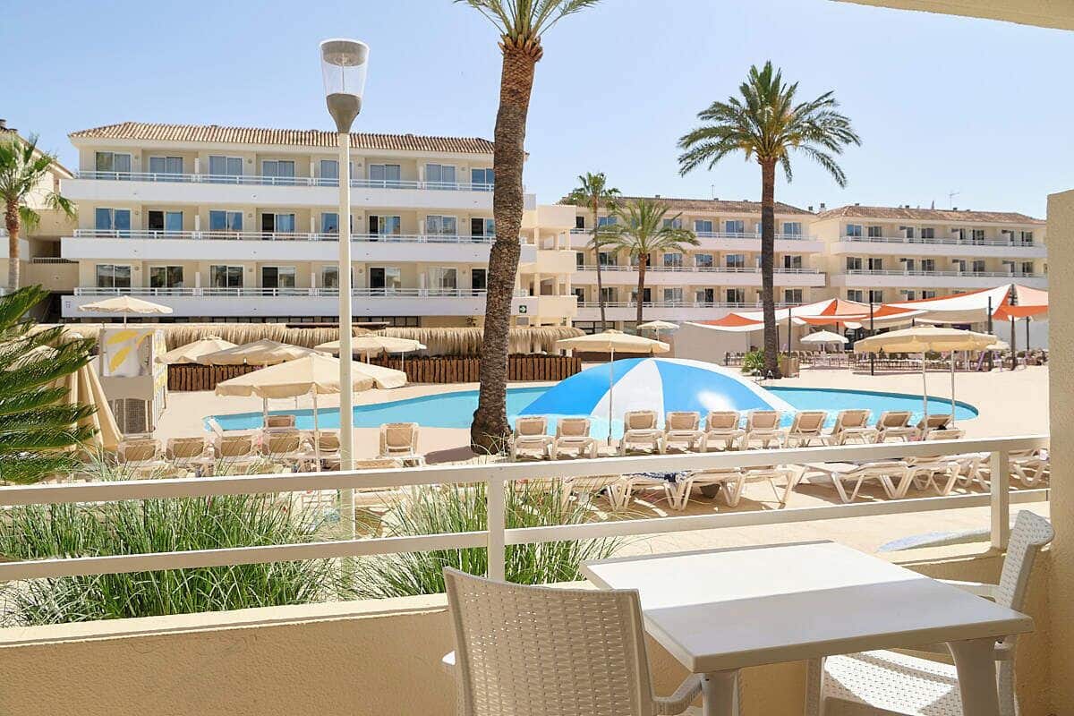 A hotel pool area with lounge chairs, umbrellas, and a clear view of the building in the background.
