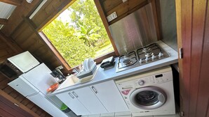 A compact kitchen with a washing machine, a stove, and a refrigerator. - Appart Bellissima Calme Paisible Entouré de Verdure (Baie-Mahault)