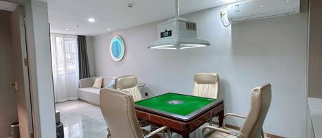 A modern dining area with a pool table, comfortable seating, and a ceiling-mounted projector.