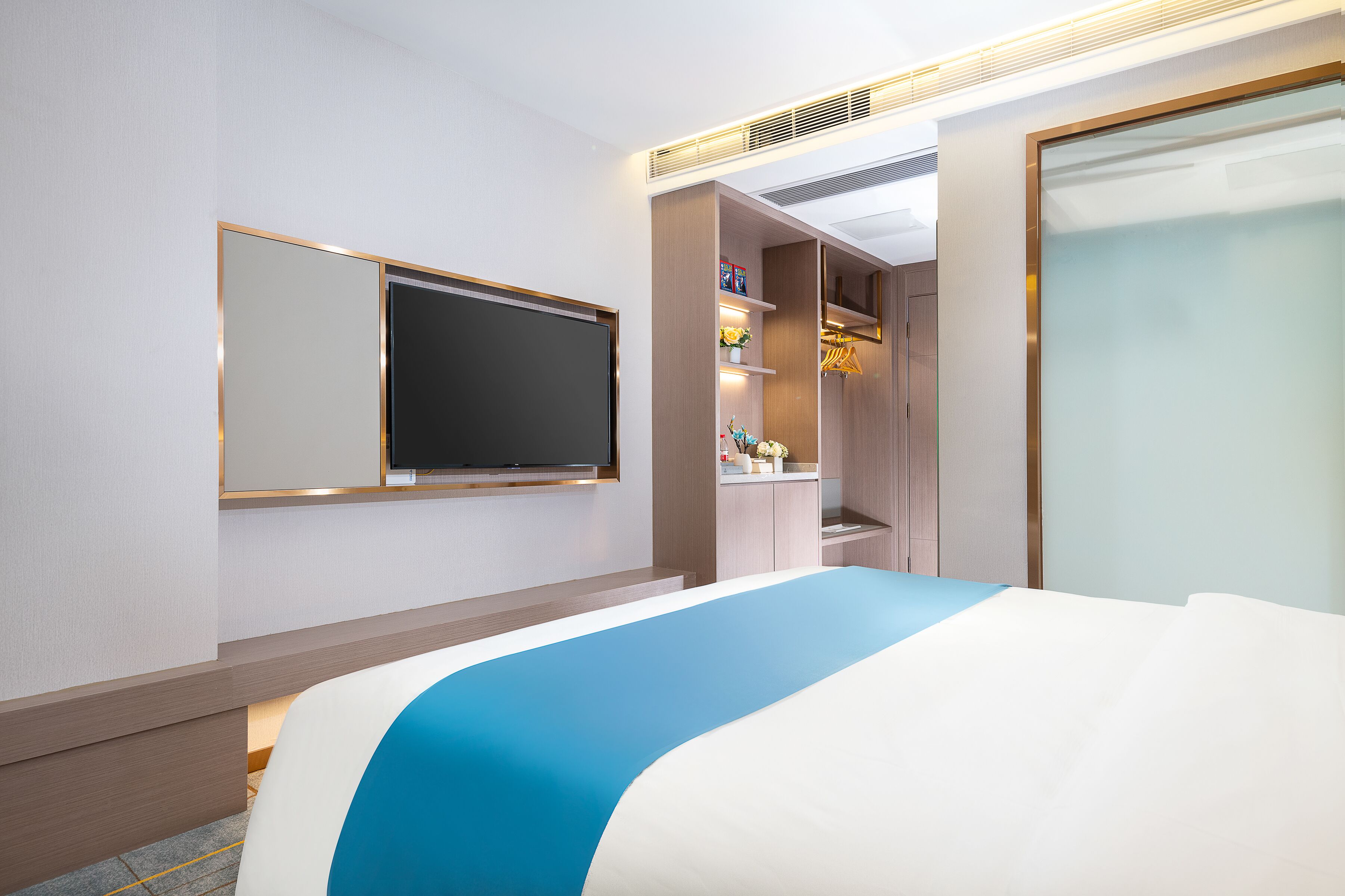 Ein Hotelzimmer mit Bett, Wand-Fernseher und begehbarem Kleiderschrank.