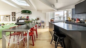 Une cuisine moderne avec un îlot central, un coin repas avec des chaises rouges et un canapé vert.