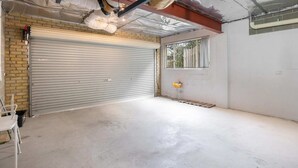 Een garage met een gesloten rolluik, een raam en een betonnen vloer.