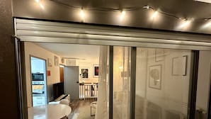 Una cocina moderna con horno empotrado, un comedor con mesa y sillas blancas, y vista al salón contiguo.