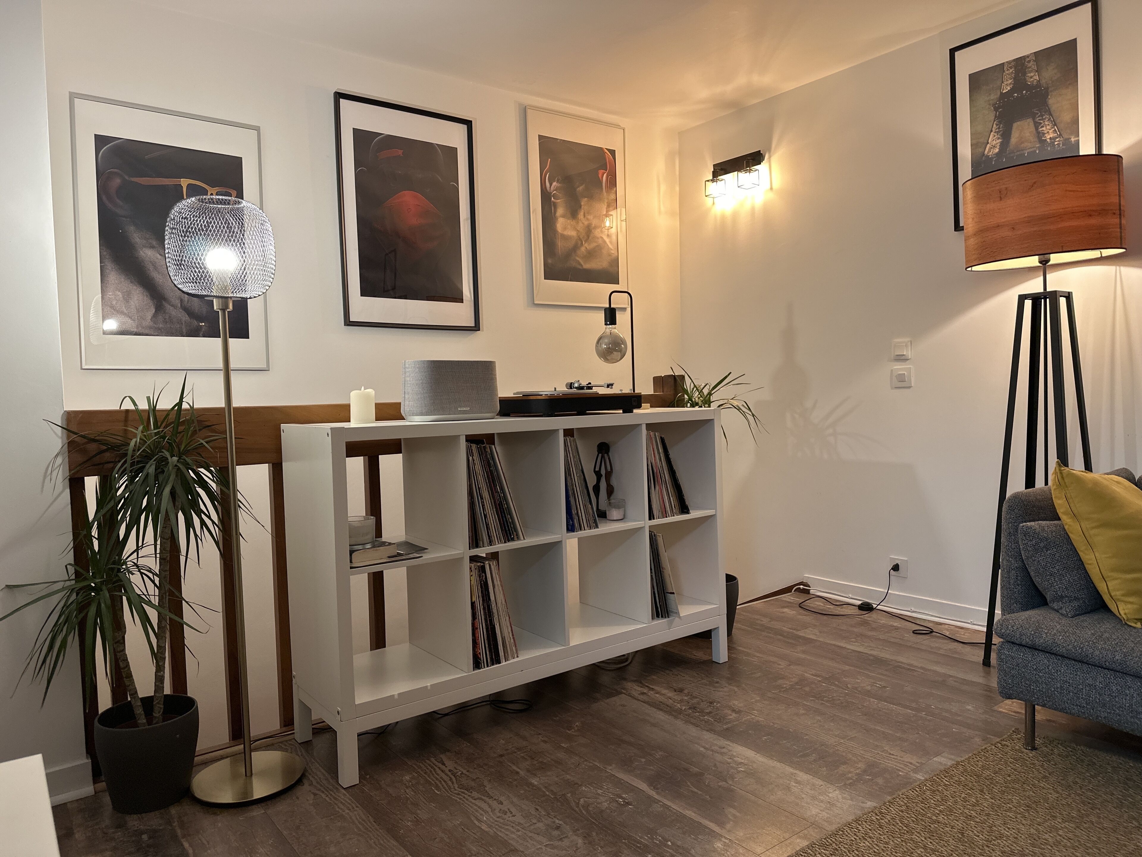 A living room with a white entertainment unit, a floor lamp, and framed pictures on the wall.