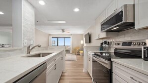 A modern kitchen with a dishwasher, oven, microwave, and stainless steel cabinets. - Completely Renovated Three Bedroom Oceanfront Condo (Ocean City)