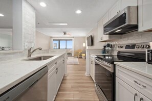 A modern kitchen with a dishwasher, oven, microwave, and stainless steel cabinets.