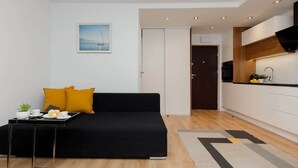 A modern living room with a black sofa, a small table with a tray, and a painting on the wall. - Air-conditioned Studio with a Balcony | Close to Pola Mokotowskie (Warszawa)