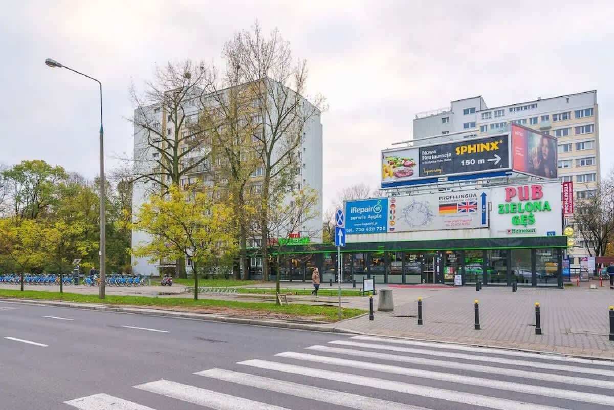 A street view with a building featuring a large billboard advertising Sphinx and a sign for iRepair Apple.