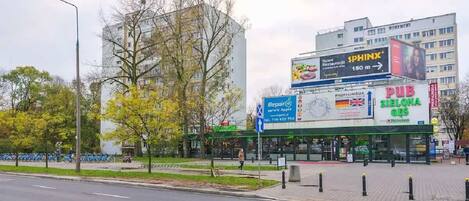 A street view with a building featuring a large billboard advertising Sphinx and a sign for iRepair Apple.