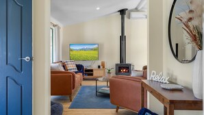 Una sala de estar acogedora con sofá, televisión, chimenea y comedor.