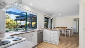 Una cocina moderna con un ventanal grande, un comedor con sillas de madera y vistas al exterior.