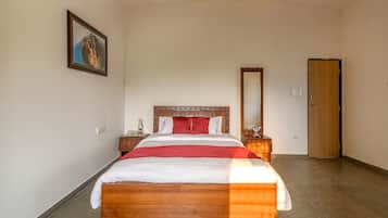 A neatly arranged bedroom with a wooden bed, a nightstand, a mirror, and a door.