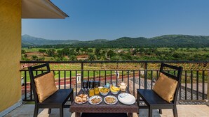 A balcony with a table set for breakfast, overlooking a scenic landscape.