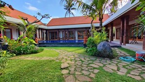 Un patio con un sendero de piedra, una piscina y plantas tropicales.