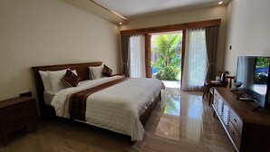 Habitación de hotel con una cama grande, televisión, cómoda y balcón con cortinas.