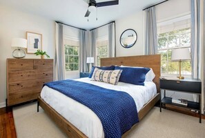 Cozy retreat with a large bed, dresser, and potted plant.
