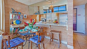 A modern kitchen with a central island, wooden chairs, and a dining table set for four.