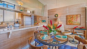 A modern kitchen with a central island, wooden cabinets, and a dining area with a round table and chairs.