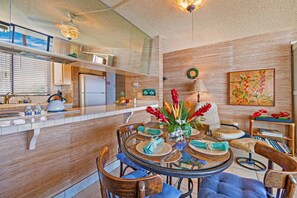 Uma cozinha moderna com uma ilha central, armários de madeira e um espaço de refeições com uma mesa redonda e cadeiras.