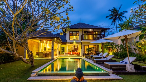 Una casa a due piani con piscina, area relax esterna e piante tropicali.
