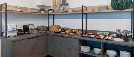 A modern kitchen with a coffee station, toaster, and various food items on shelves.