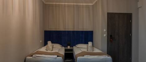 A hotel room with two beds, a dark wooden door, and a patterned carpet.