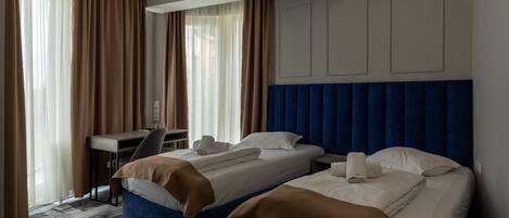Een hotelkamer met twee bedden, een bureau en een stoel.
