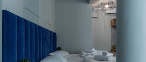 Habitación de hotel moderna con una cama grande, cabecera azul y toallas impecables.
