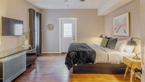 A bedroom with a bed, bedside table, lamp, ceiling fan, and a door. - The Hera! Luxury Mansion in Montrose w/ Pool 4BR+1 (Houston)