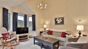 A living room with a TV, sofa, and rocking chair.