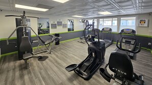 Ein Fitnessstudio mit Laufbändern, Crosstrainern und Gewichten.