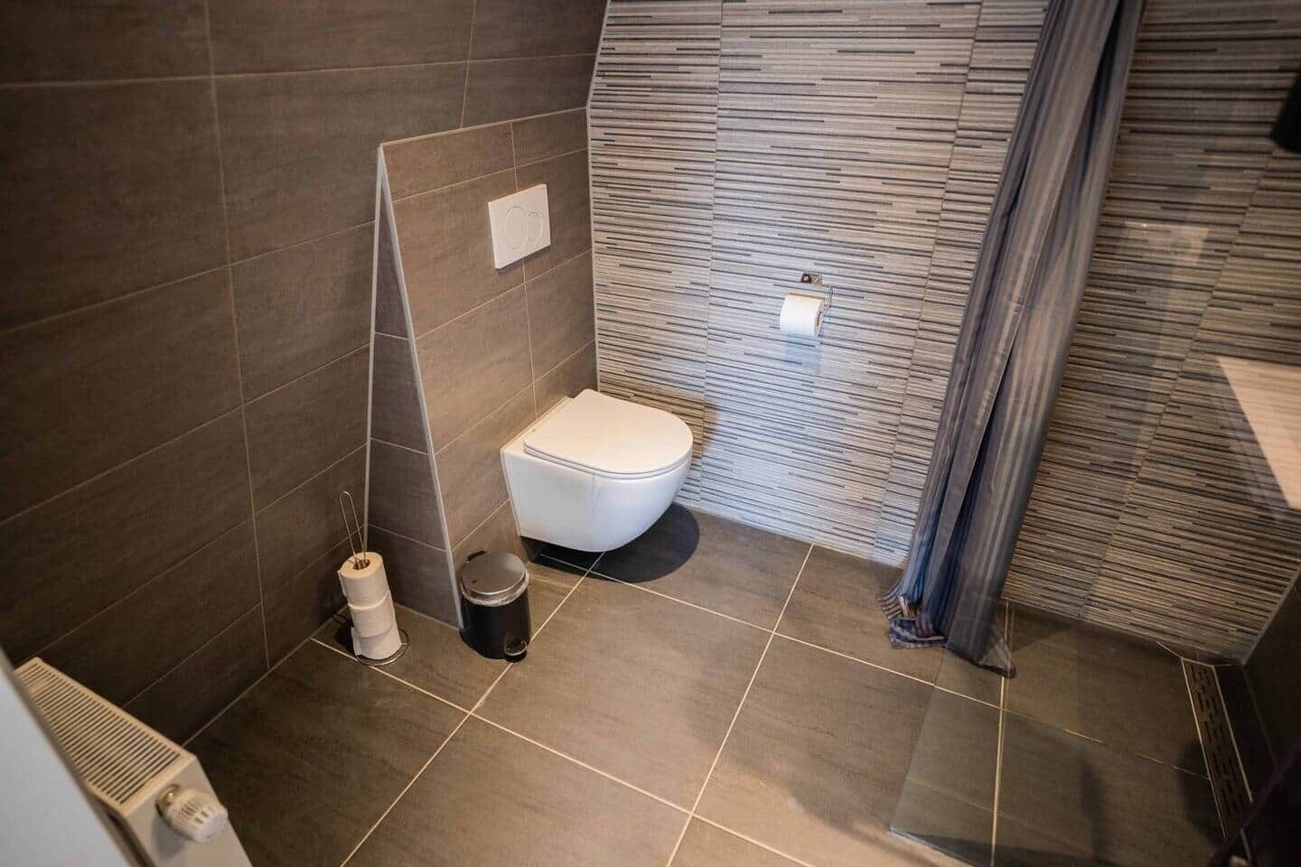 Un baño moderno con inodoro, ducha y toallero.