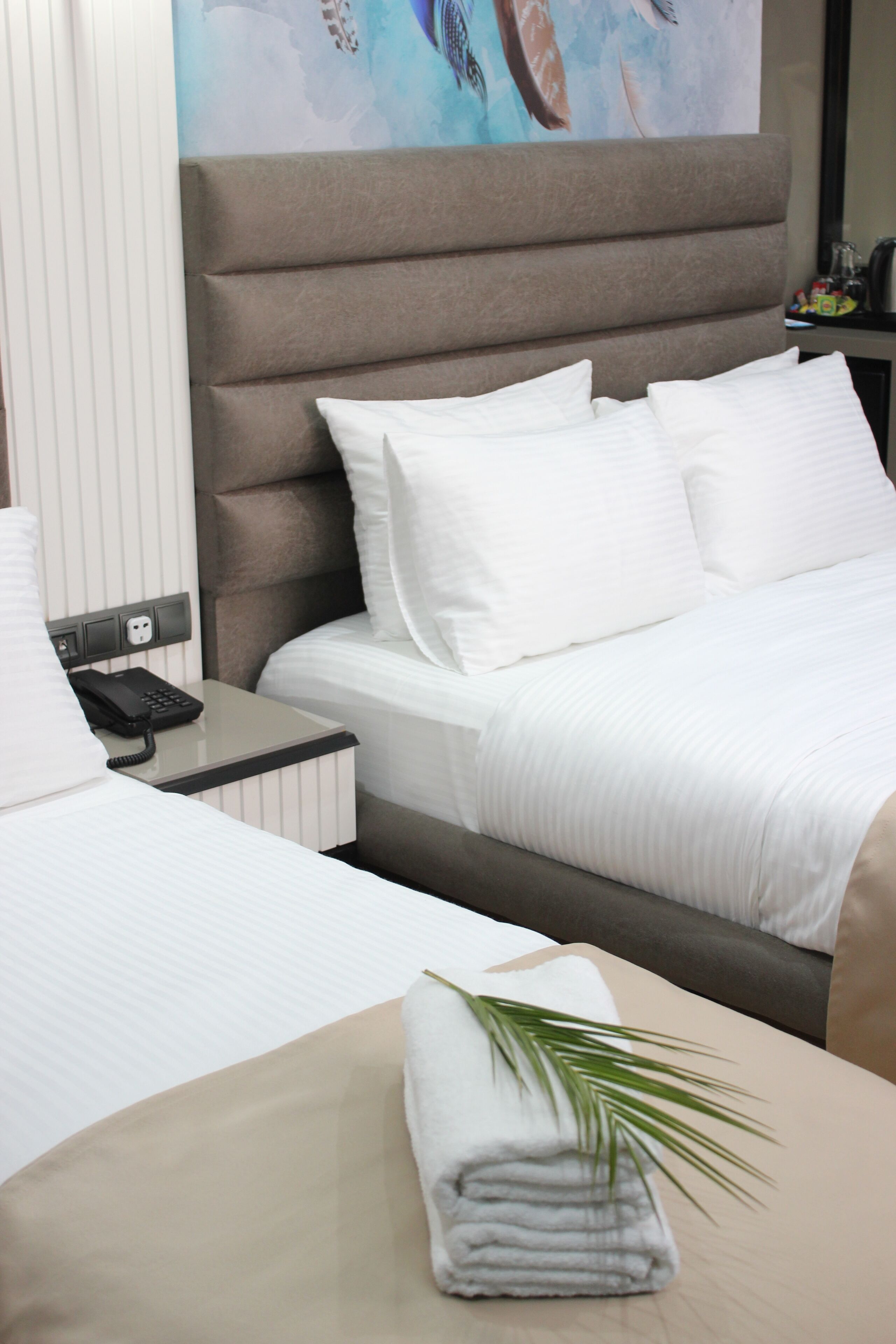 Une chambre d’hôtel avec un lit, une table de chevet avec un téléphone et une serviette pliée posée sur une table.