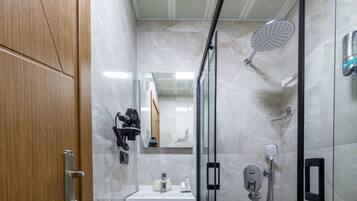 Un baño moderno con puerta de madera, lavabo de mármol, cabina de ducha de vidrio y un espejo.