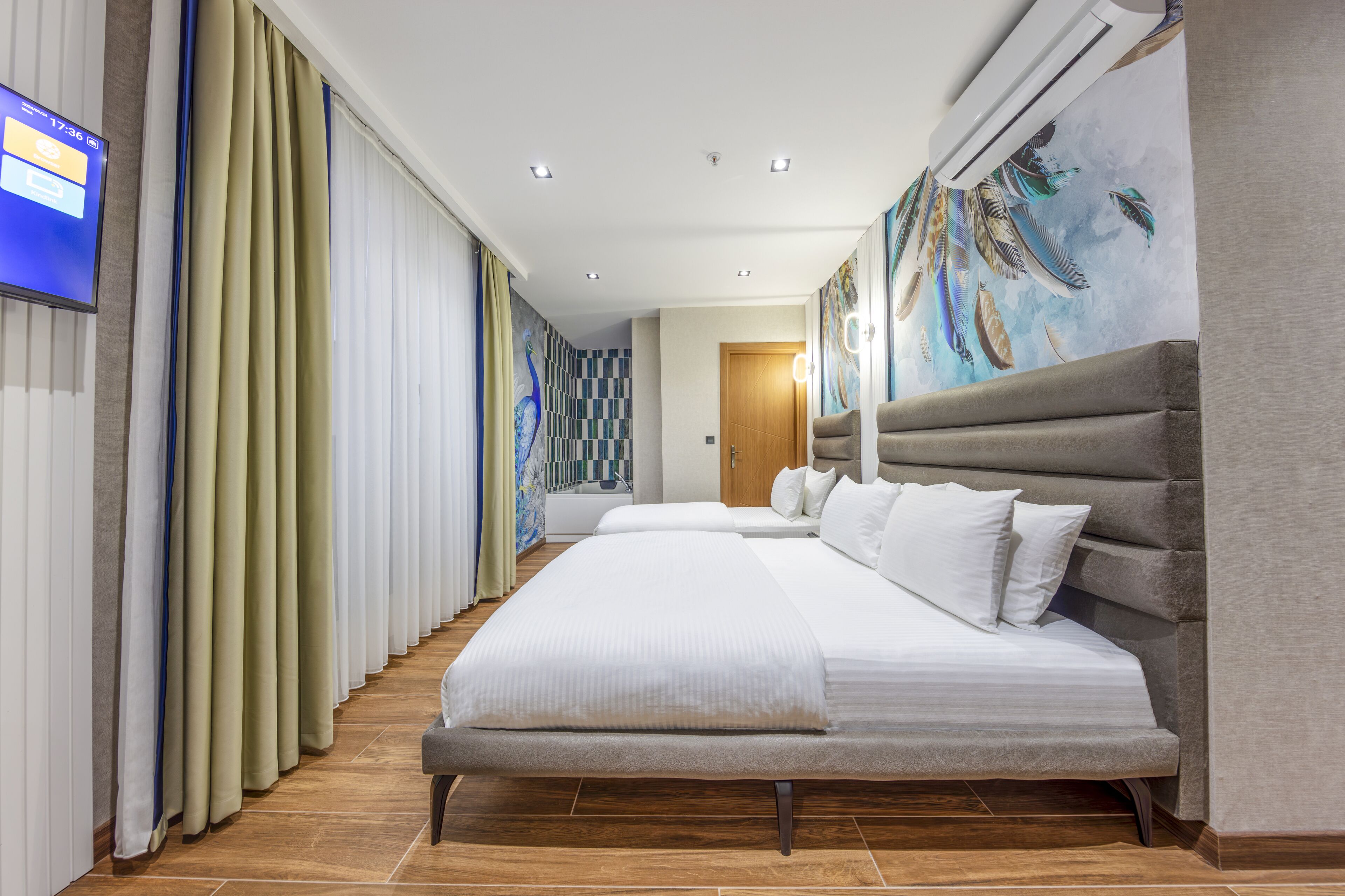A hotel room with a large bed, a television, and a mural on the wall.