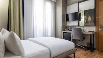 A hotel room with a bed, a desk with a chair, a television, and a mirror.