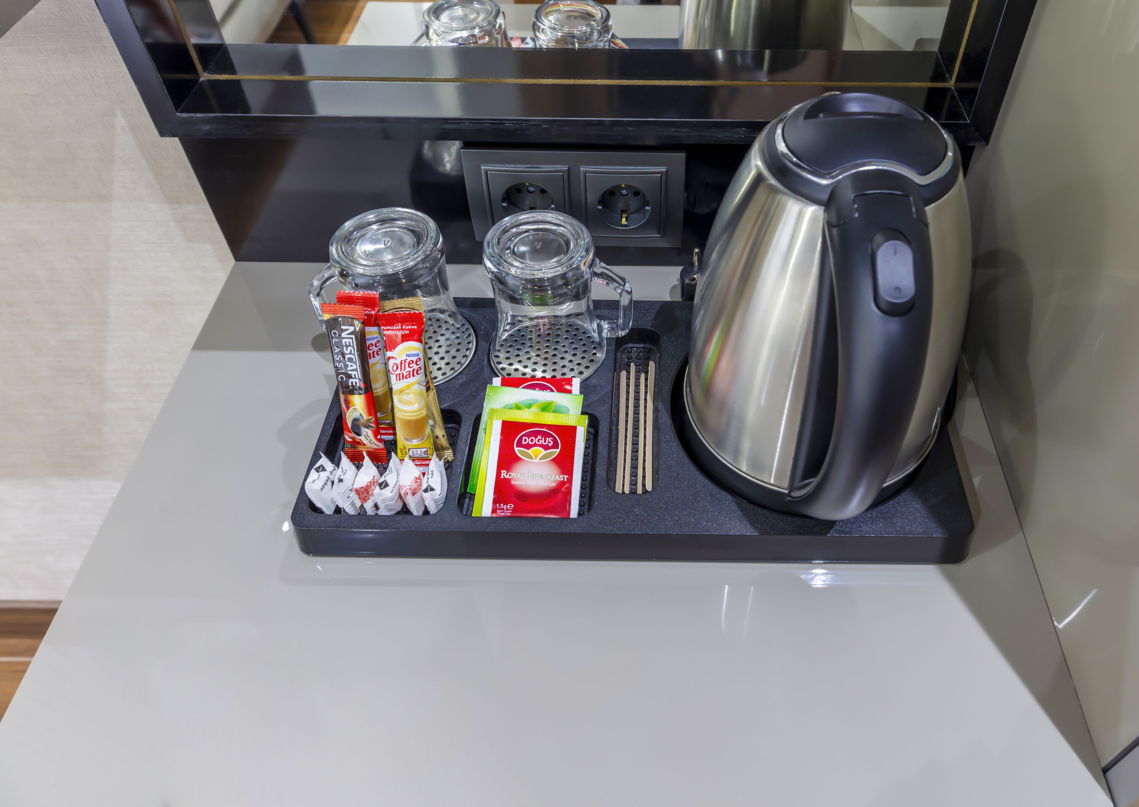 Una encimera de cocina con una cafetera, un hervidor, un molinillo de café y diferentes cápsulas y paquetes de café.